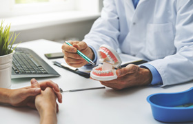 Dentist showing patient model of teeth