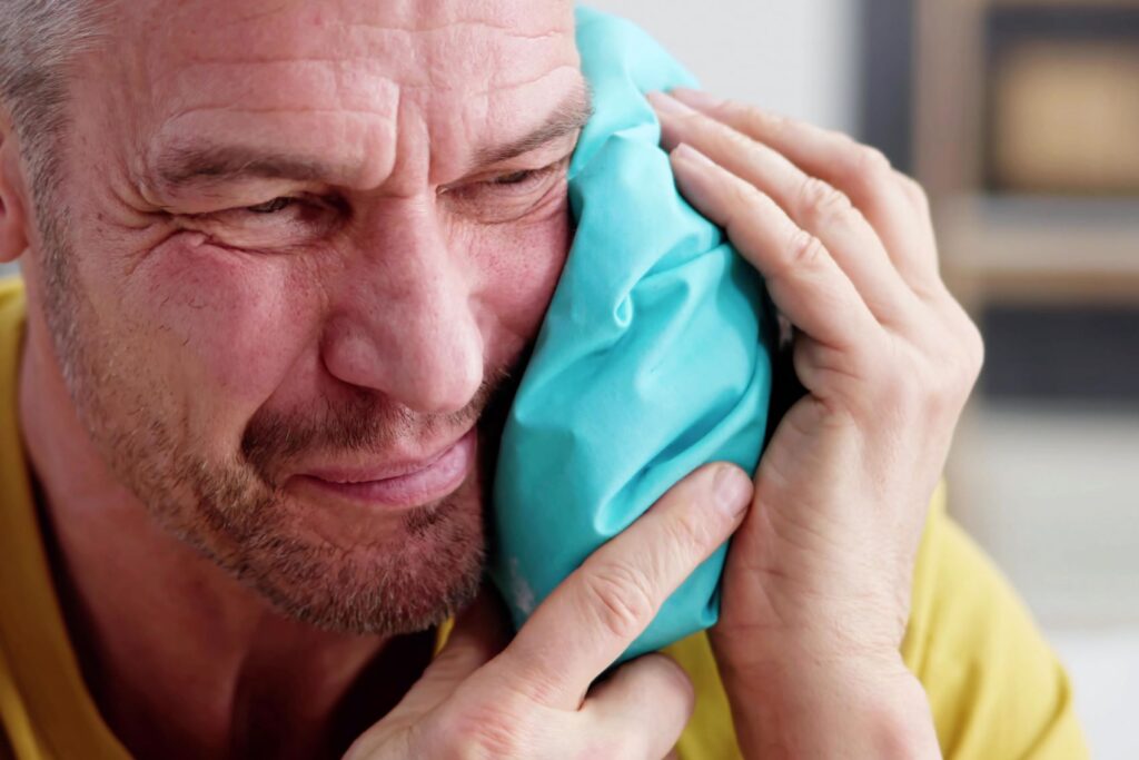 A man holding a bag of ice to his cheek